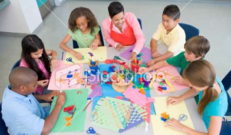 teacher and children in a classroom with coloured paper