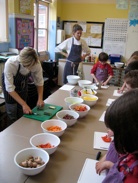 Teacher demonstrating cooking skills to children at school